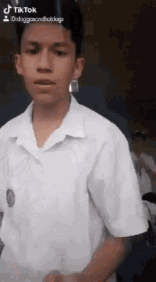 a young man in a white shirt is standing in front of a camera .