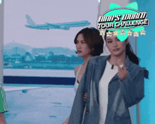 two women standing in front of a sign that says ' aah 's world tour challenge ' on it