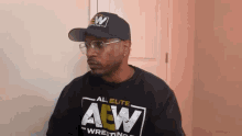 a man wearing a hat and glasses is wearing a shirt that says all elite wrestling