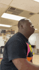 a man in a black shirt is standing in a room with a ceiling fan