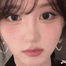 a close up of a woman 's face with earrings and a tear coming out of her eye .