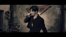 a man singing into a microphone in front of a graffiti wall with a detour sign
