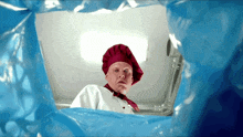 a man in a chef 's hat looks out of a blue bag