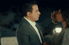 a man in a suit and tie is touching the face of a woman in a white dress .