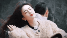 a man is holding a woman in his arms with her eyes closed .
