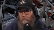 a man with a beard is wearing a hat and headphones .