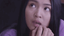 a close up of a woman 's face with a purple shirt on .