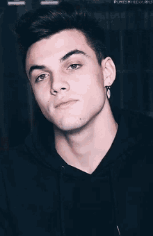 a close up of a young man wearing a black hoodie