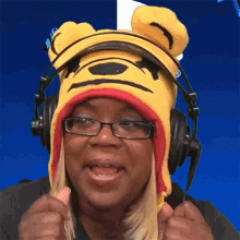 a woman wearing a winnie the pooh hat and headphones is giving a thumbs up