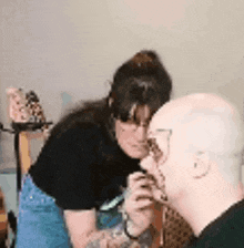 a woman is applying makeup to a bald man 's face in a room .