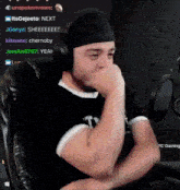 a man wearing headphones is sitting in front of a microphone and covering his mouth .