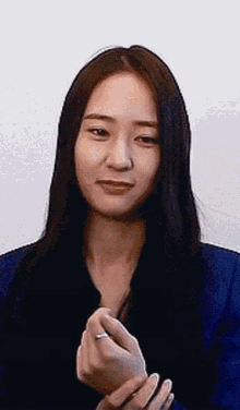 a woman with long black hair is wearing a blue jacket and a ring on her finger