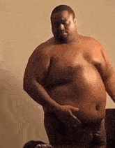 a shirtless man with a very large belly is standing next to a table .