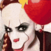 a woman dressed as a clown is holding a red balloon in her hand .