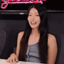 a woman with long hair is sitting at a table with a computer mouse and smiling .