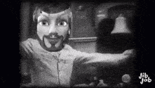 a black and white photo of a puppet with a beard and a bell .
