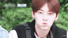 a young man with a camera around his neck making a funny face
