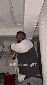a man is standing in a room with the words blackout.g97 on the bottom right