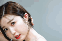 a close up of a woman 's face with a ponytail and earrings