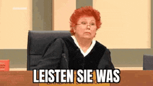 a judge is sitting at a table in a courtroom with a microphone and a sign that says listen sie was .