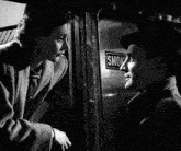 a man and woman are talking in front of a sign that says smok