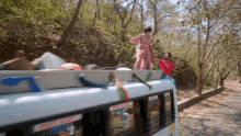 a man and a woman are standing on top of a white bus with the word t on the side