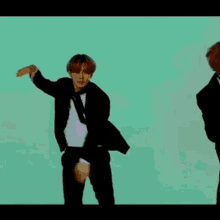 a group of men in suits and ties are dancing in front of a green background .