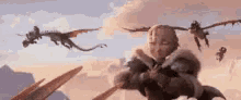 a group of dragons are flying over a person holding a sword .