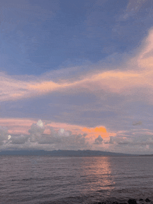 a sunset over a large body of water with mountains in the background
