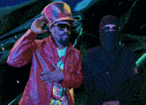 a man in a red jacket stands next to another man in a black jacket