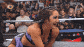 a woman in a wrestling ring with a cw logo on the bottom left
