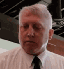 a man in a white shirt and black tie is making a funny face .