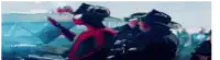 a man in a spiderman costume is talking to a fireman in a crowd of people .