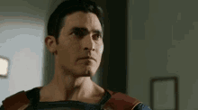 a man in a superman costume is standing in a room and looking at the camera .