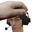 a man wearing headphones and glasses is being touched by a person 's hand .