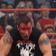 a wrestler with blood on his face is wearing a black shirt that says ' nightmare '
