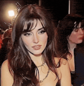 a close up of a woman 's face wearing a necklace and a black dress .