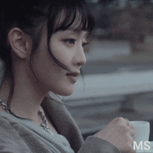 a close up of a woman holding a cup with the letters ms visible