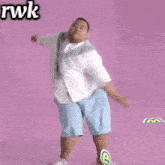a man in a white shirt and blue shorts stands in front of a pink background with rwk written above him