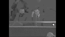 a man in a suit and tie is sitting in the stands of a stadium .
