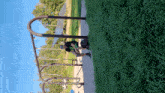 a person wearing a black shirt with a green circle on it is standing on a swing set