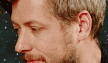 a close up of a man 's face with a beard and a black shirt