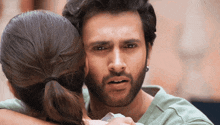 a man with a beard is hugging a woman in a green shirt