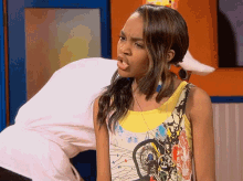 a girl in a yellow tank top is making a silly face
