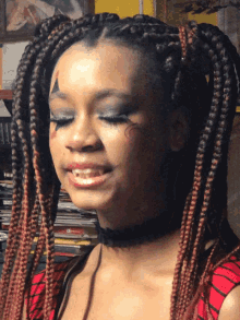 a woman with braids and a tattoo on her face looks down