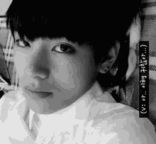 a black and white photo of a young man with foreign writing on the bottom right