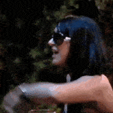 a man with blue hair is making a funny face while pointing at something .