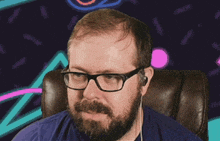 a man with glasses and a beard is sitting in a chair