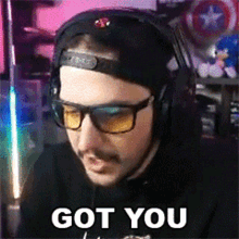 a man wearing headphones and sunglasses says `` got you '' while sitting in front of a computer .