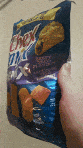 a person is holding a bag of chex mix taco flavour chips